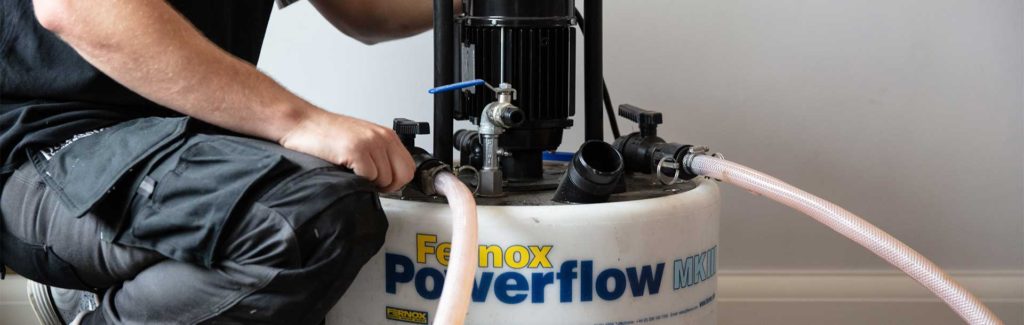 An engineer setting up a Powerflushing machine in order to cleanse a central heating system