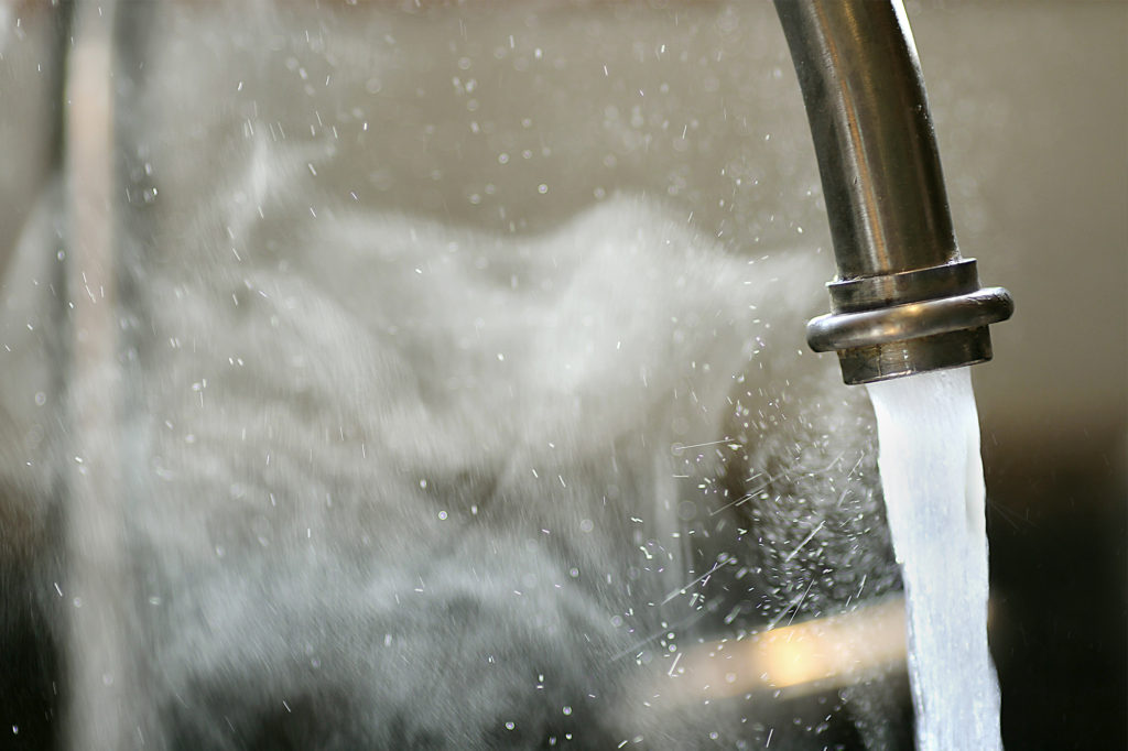 a kitchen tap running with clouds of steam from an instantaneous hot water system