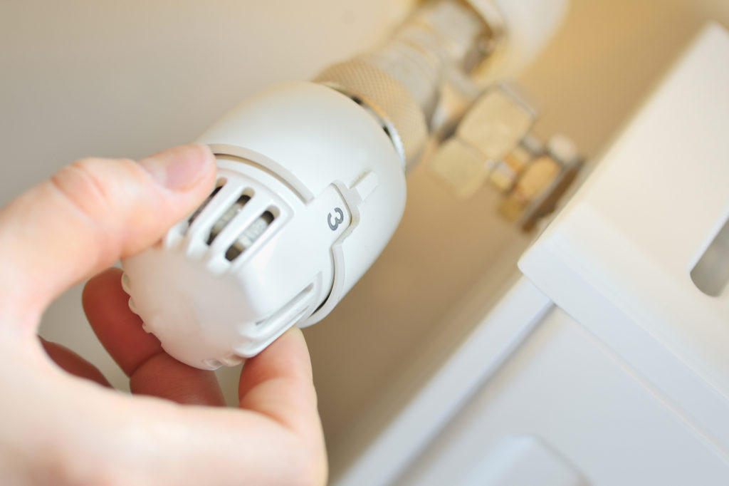 A hand manually adjusting thermostatic radiator valves