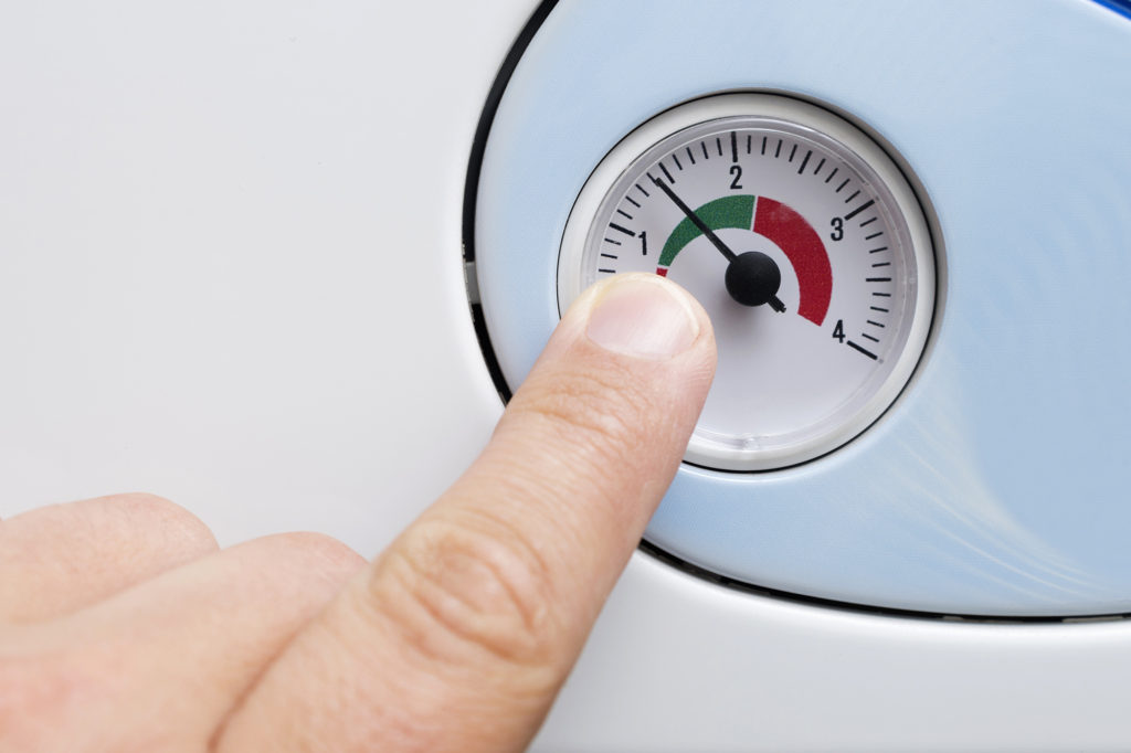 a finger points to a gauge which tells you when you need to re-pressurise your central heating system
