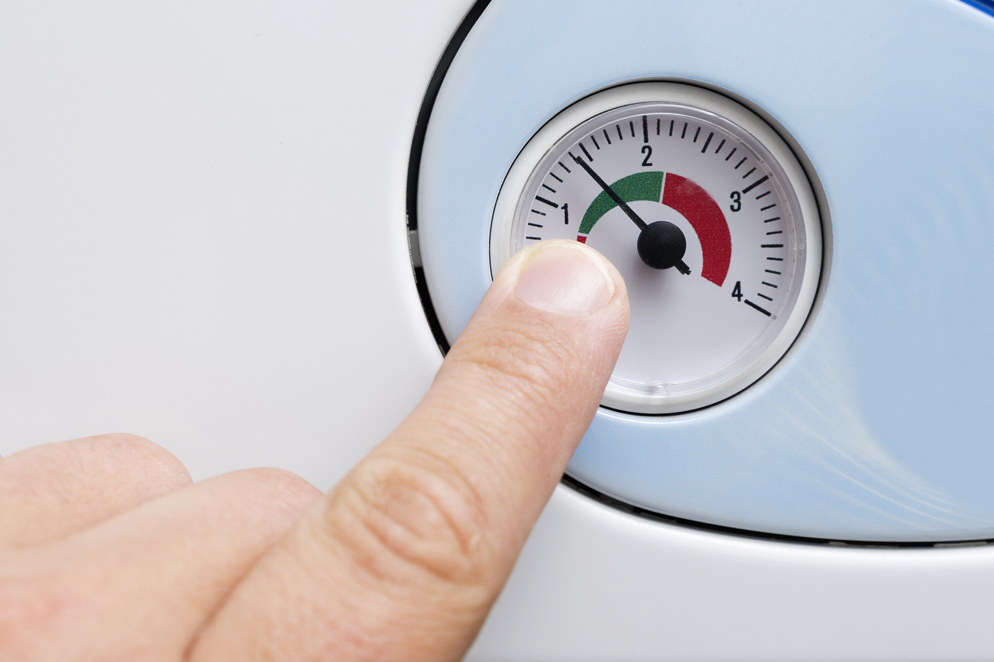 a finger points to a gauge which tells you when you need to re-pressurise your central heating system