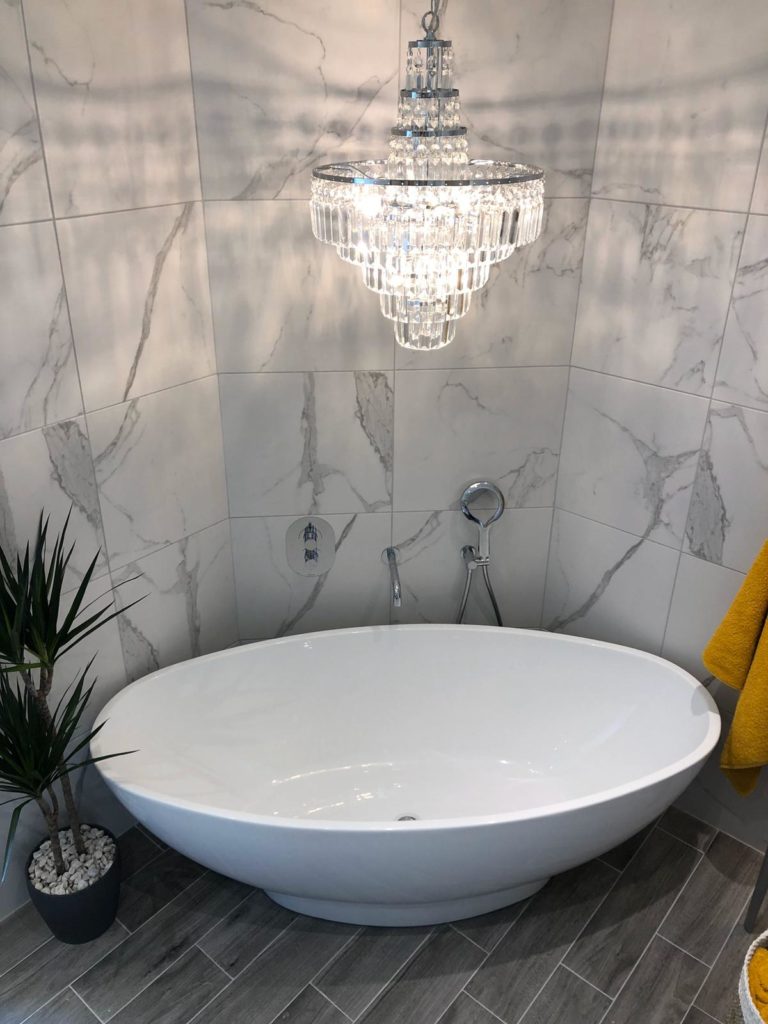 Bath and chandelier feature in luxury bathroom conversion from bedroom by Parkstone Yorkshire