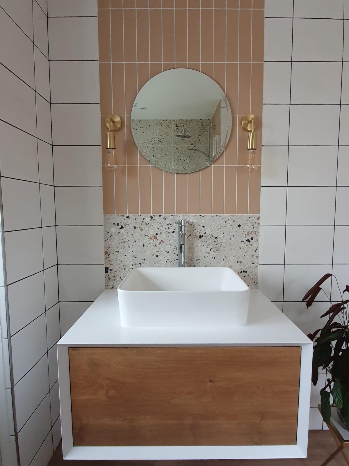 Straight swap bathroom front view of vanity unit complete, comprising of a white and wood effect cupboard and sink mounted on top with mono-mixer tap. 2 types of tiles and mirror with wall mounted pendant lighting.