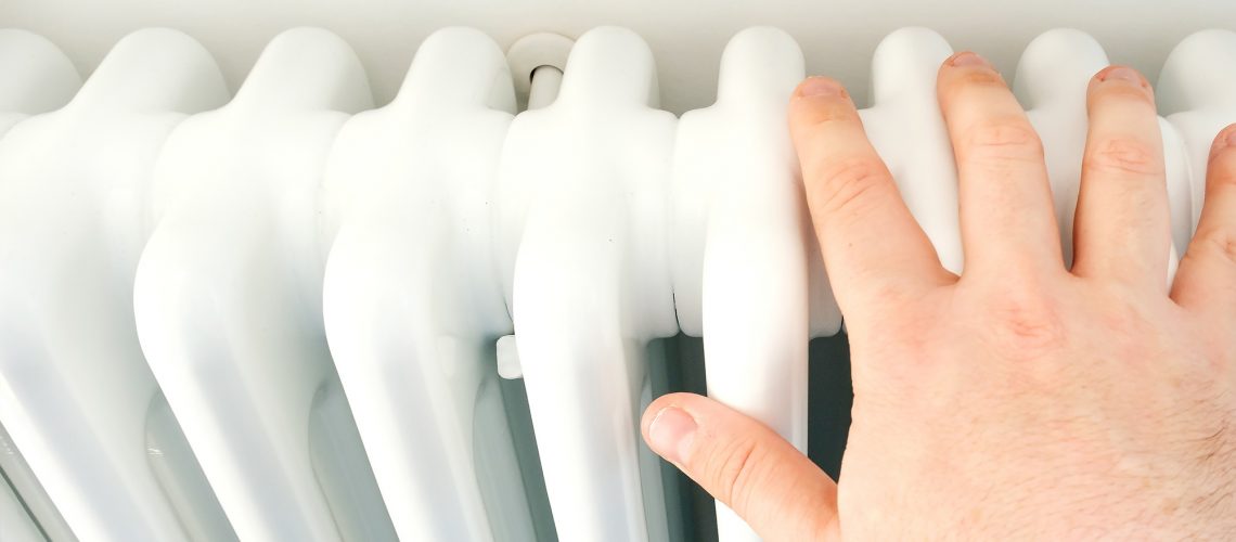 A hand on the radiator showing how to check your heating in the summer before you need it in the winter