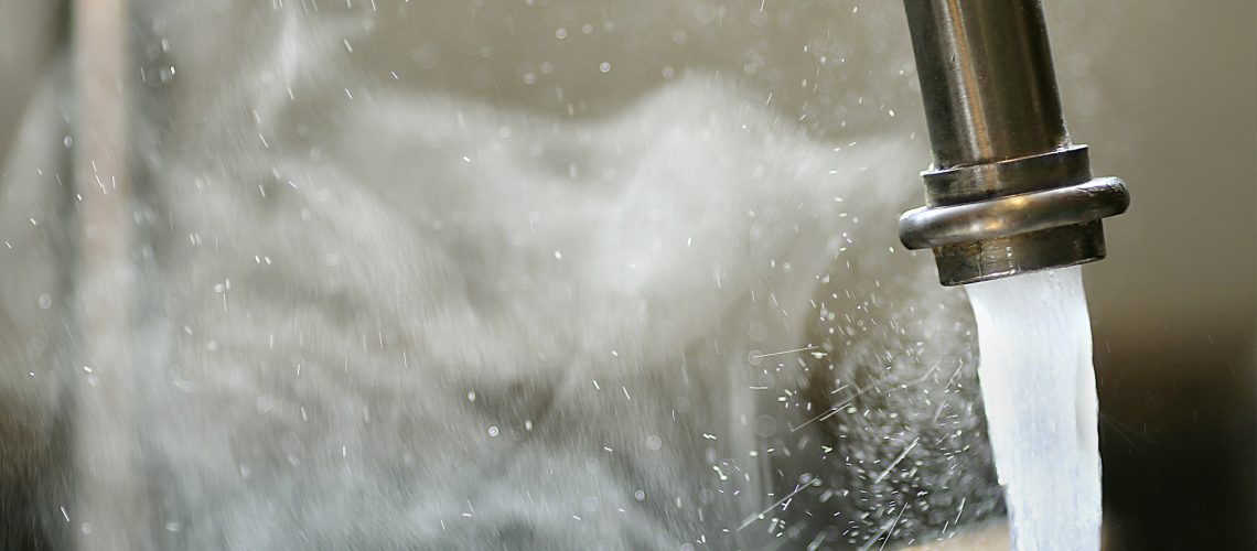 a kitchen tap running with clouds of steam from an instantaneous hot water system