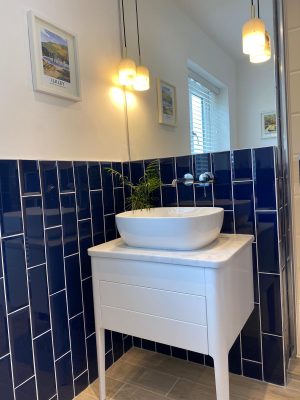 kitchen to bedroom conversion basin on table in front of blue gloss vertical brick style tiles with mirror and hanging lights