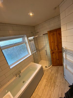 new bath, curved shower cubicle and white tessellating tiles and bathroom door open