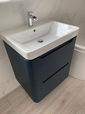 Bathroom refresh close up image of floating sink and cupboard unit in black and white fixed to wall under window.