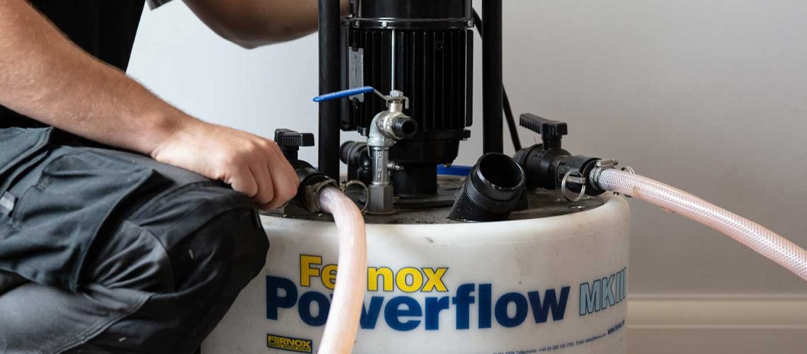 An engineer setting up a Powerflushing machine in order to cleanse a central heating system