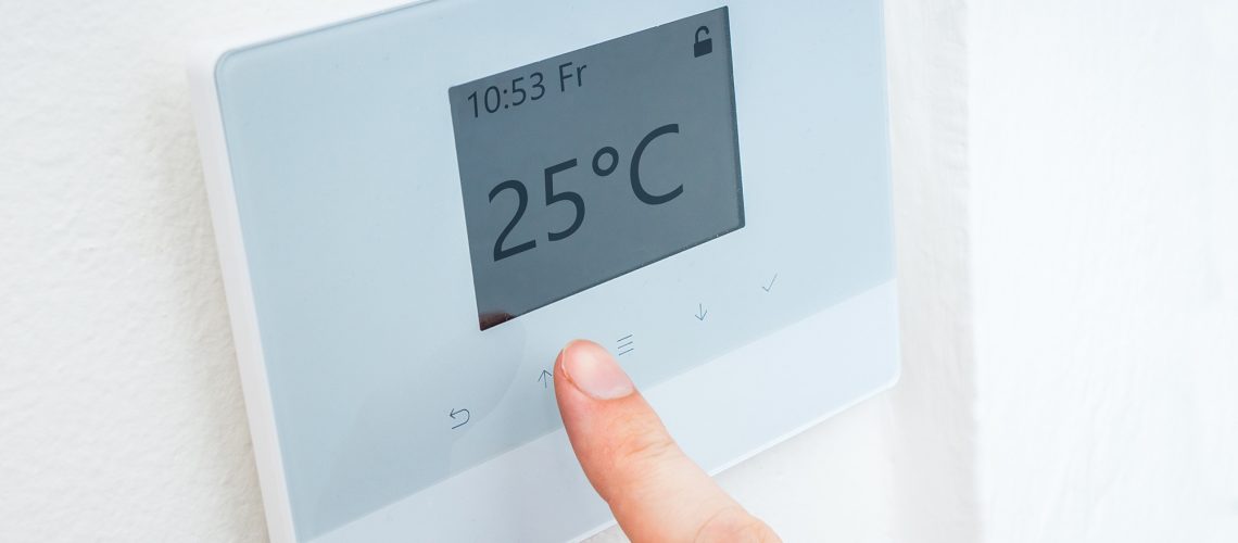 A finger used to adjust a digital room thermostat