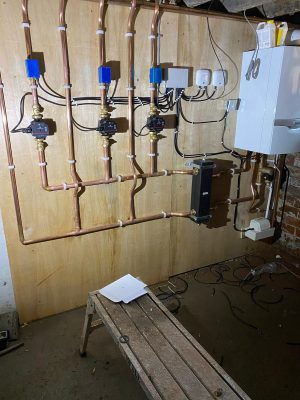Large heating system pipework mounted on plywood wall for 3 circuits connected to boiler via a low loss header