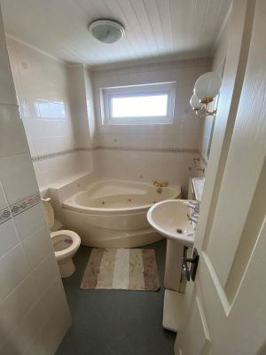 compact bathroom dated corner bath with toilet and sink on opposite walls losing floor space