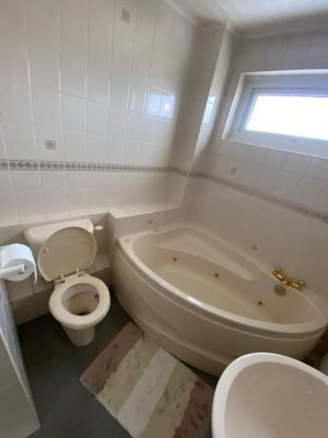 compact bathroom dated corner bath with toilet and sink on opposite walls losing floor space