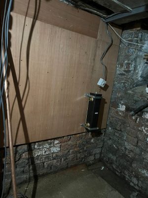 convert offices into a house project shows plywood cladding on cellar wall with Vaillant low loss header fixed at the bottom right hand corner