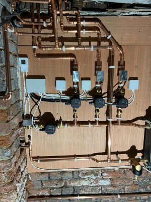 convert offices into a house project shows central heating and hot water circuits mounted on a plywood covered cellar wall