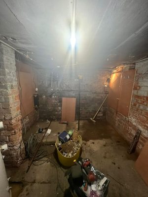 convert offices into a house project shows preparation work in cellar for new heating system by installing plywood on the cellar walls ready to hang heating components on