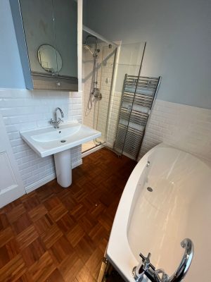 uneven bathroom floor showing existing bath, sink and shower cubicle and towel rail